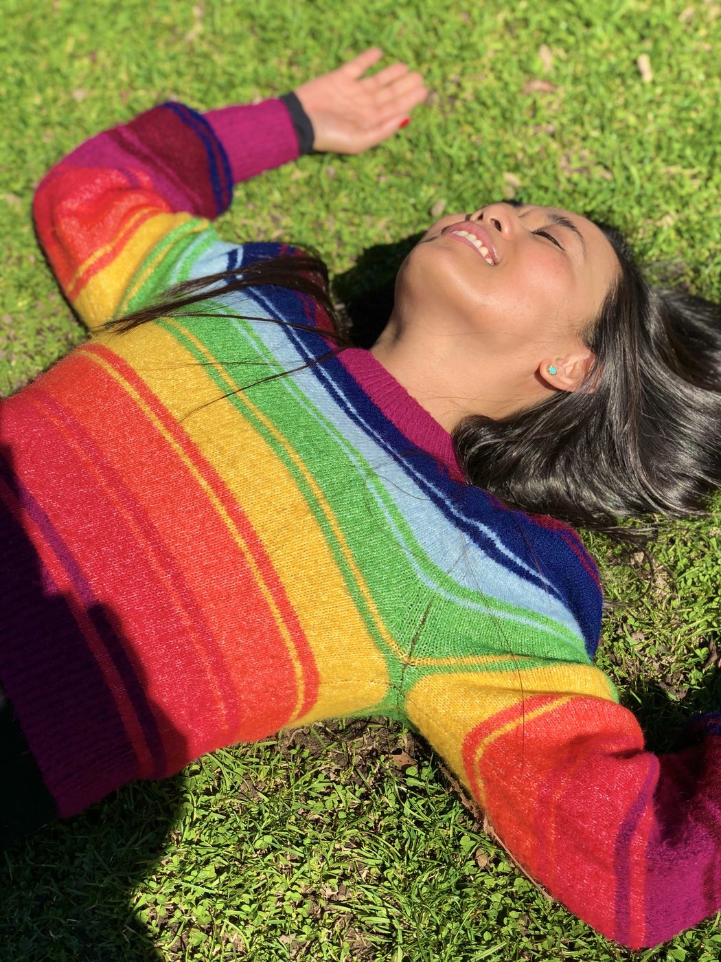 Abby Salazar smiling in a rainbow sweater